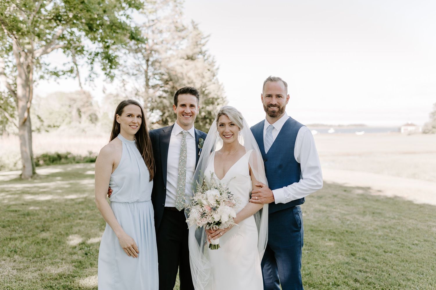 Wedding celebration group poses together on sunny spring afternoon.
