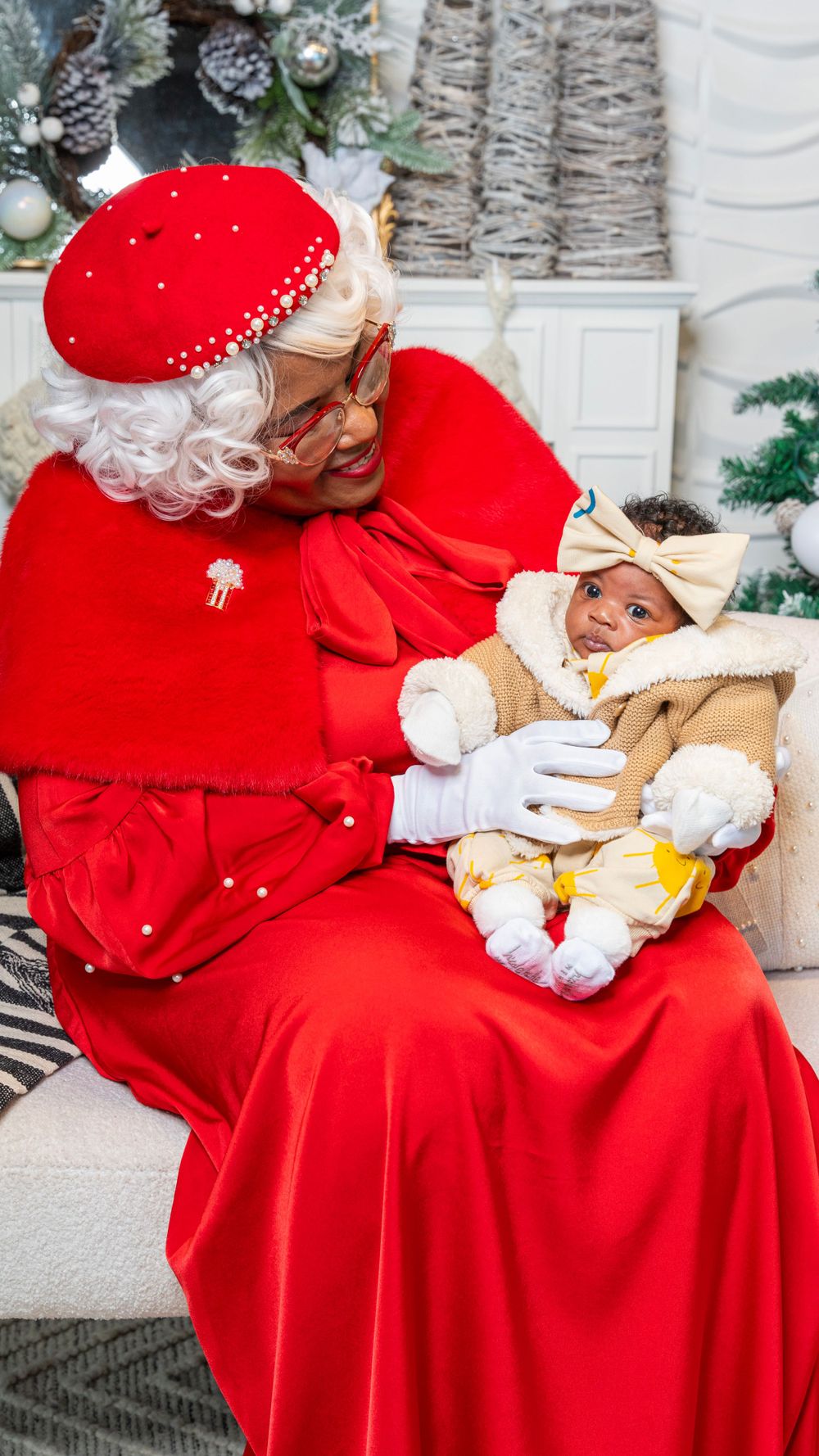 Traditional holiday scene with Santa Claus holding an infant in festive setting.
