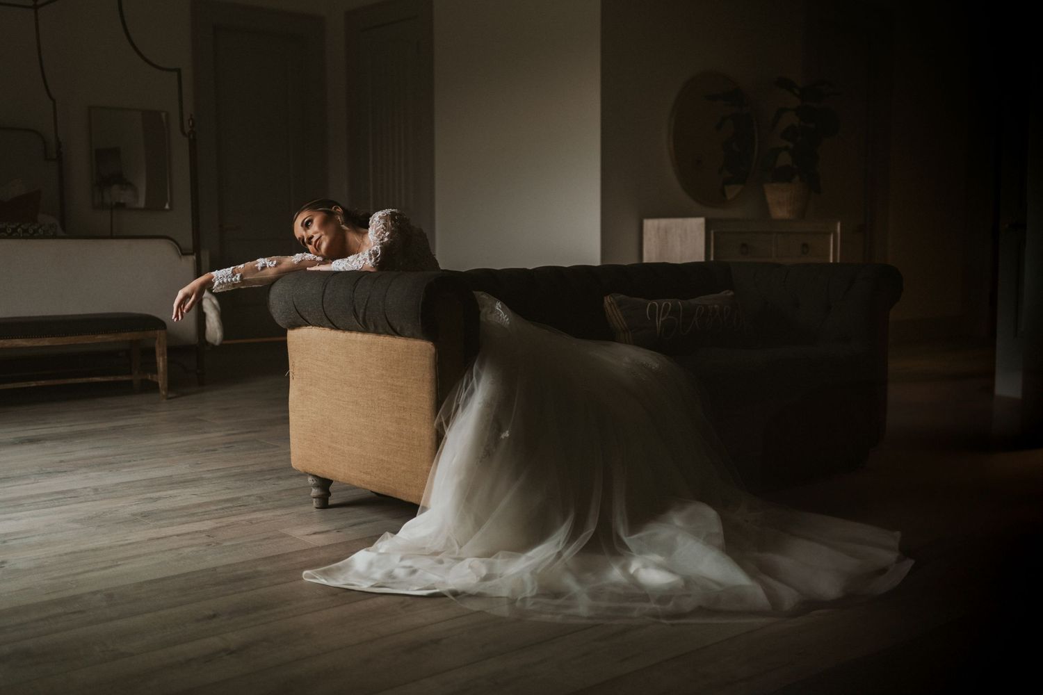 Couple resting on couch in moody dark living room with flowing fabric on floor.