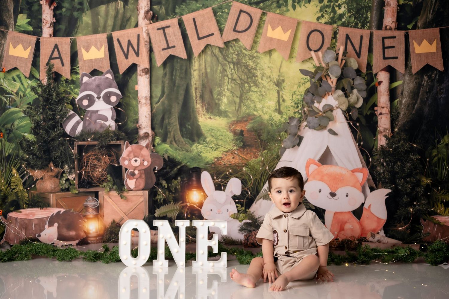Woodland themed first birthday photo setup with forest backdrop and animal decorations.