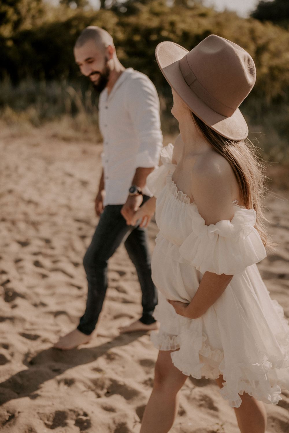 Couple in white and denim sharing intimate moments on a sandy beach at sunset.