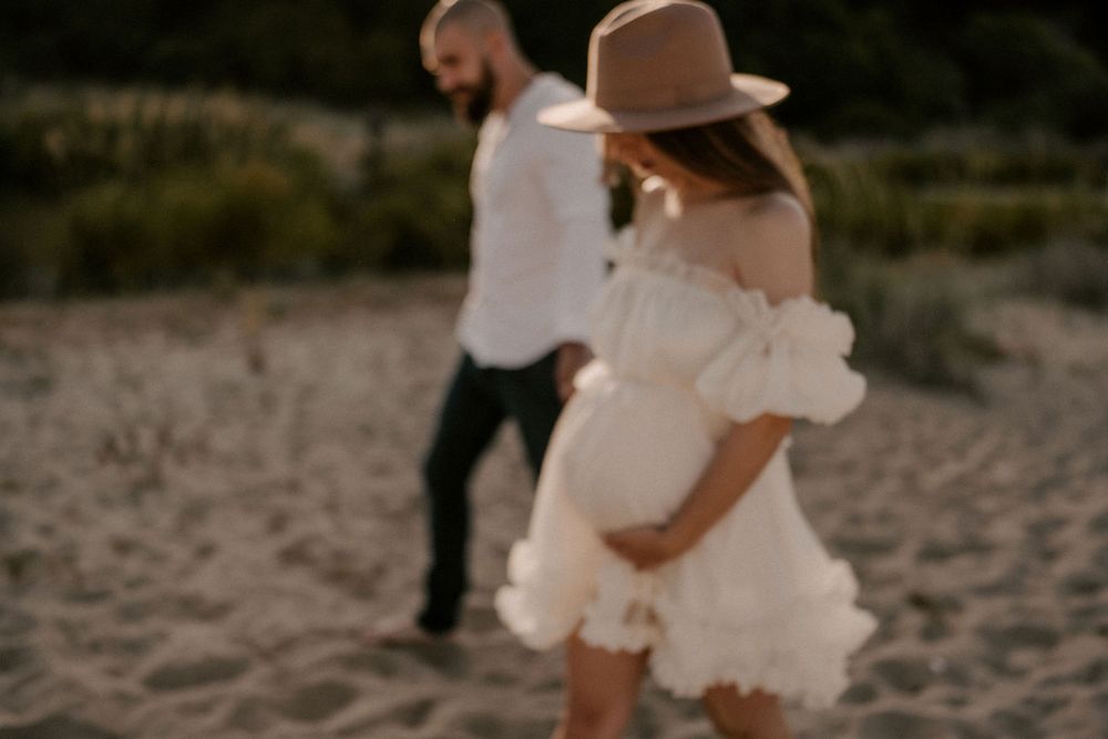 A couple walks together on a sandy beach path during golden hour.