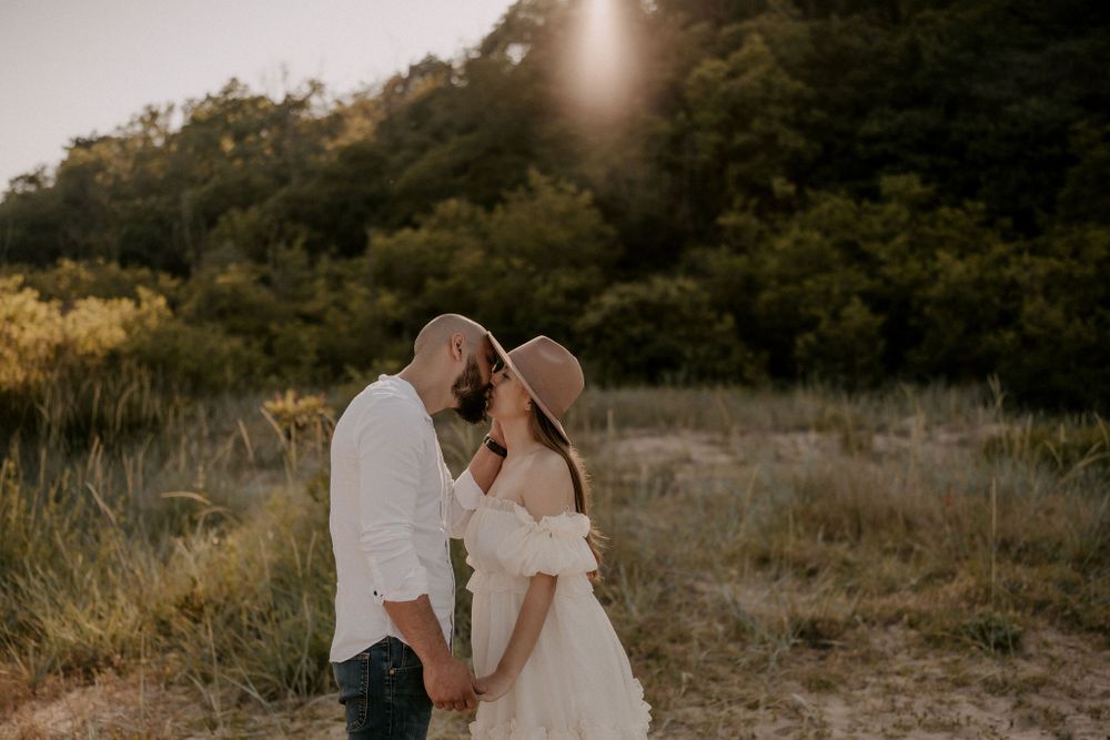 Romantic sunset photoshoot with couple embracing in natural outdoor setting.