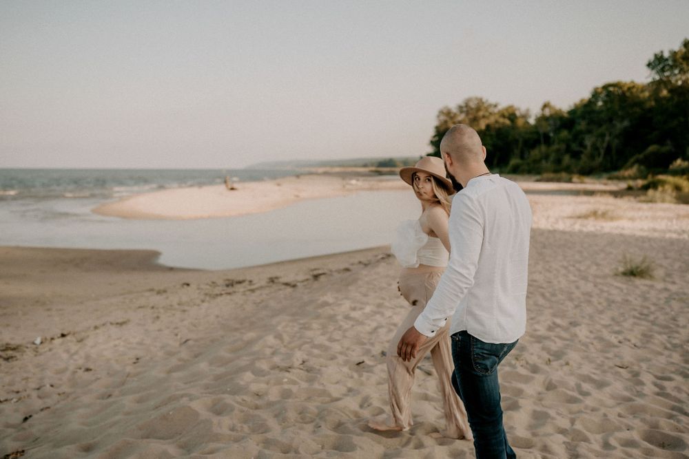 Couple walking along expansive beach shoreline during golden hour.
