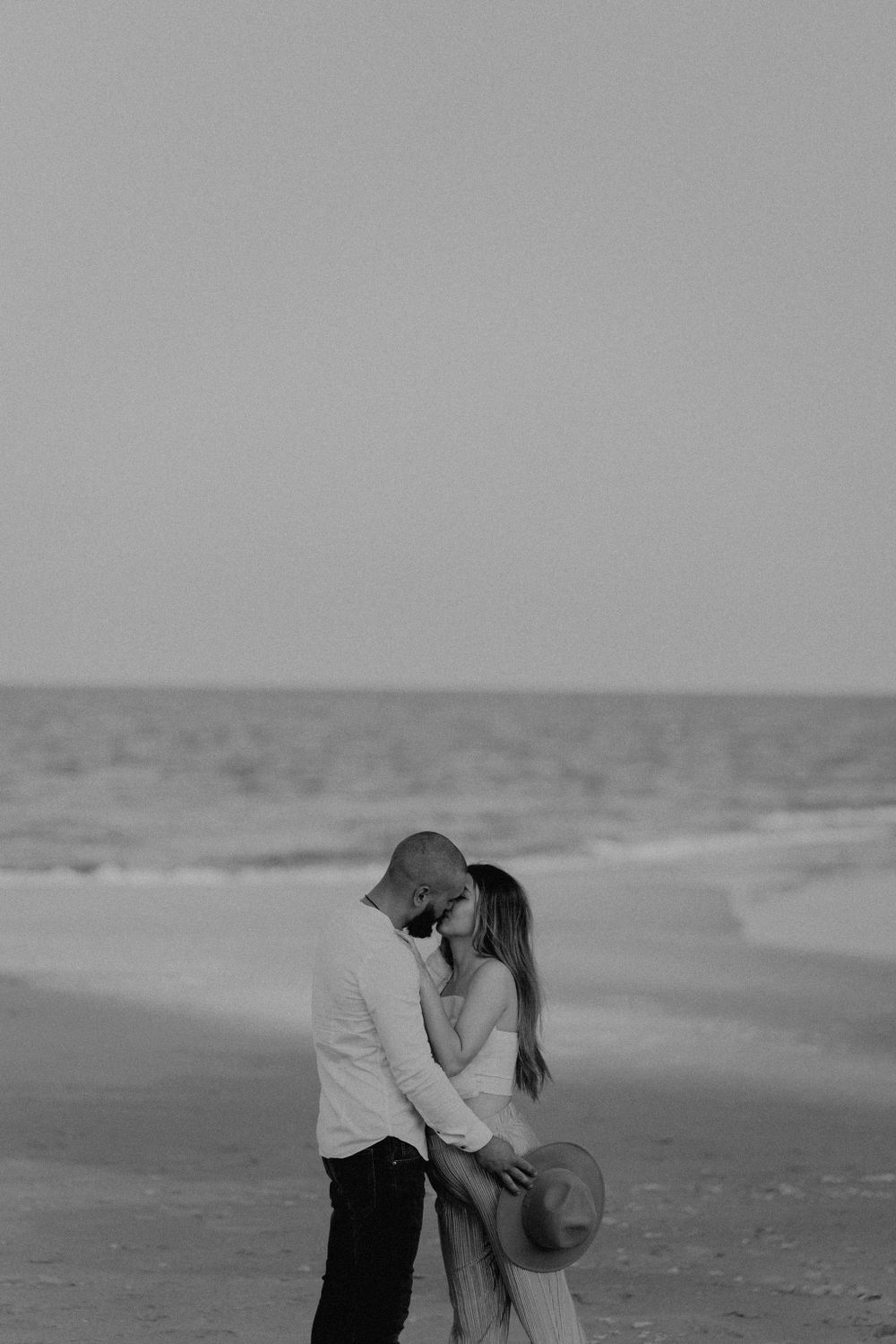A tender black and white beach portrait of a couple sharing an intimate moment.