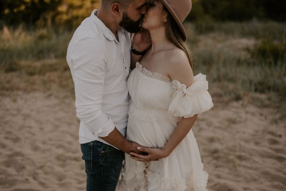 Intimate moments captured between couple during beach maternity photoshoot.