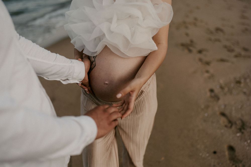 White flowy dress and beige outfit create a romantic silhouette against the beach backdrop.