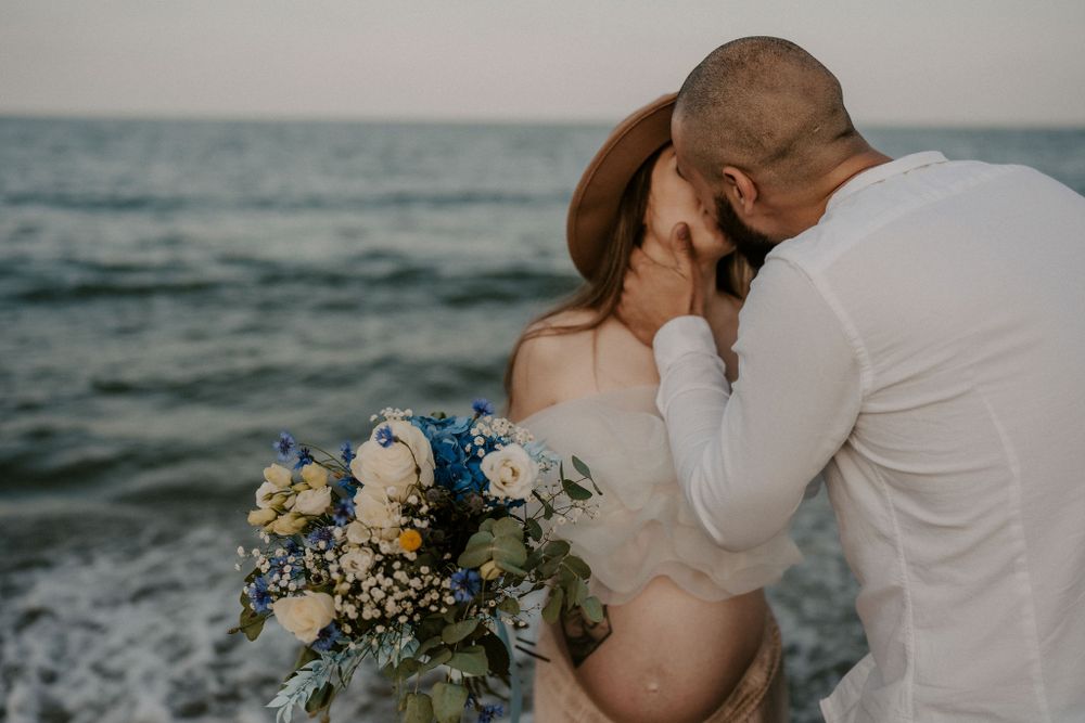 Intimate beachside maternity session with couple embracing at sunset.