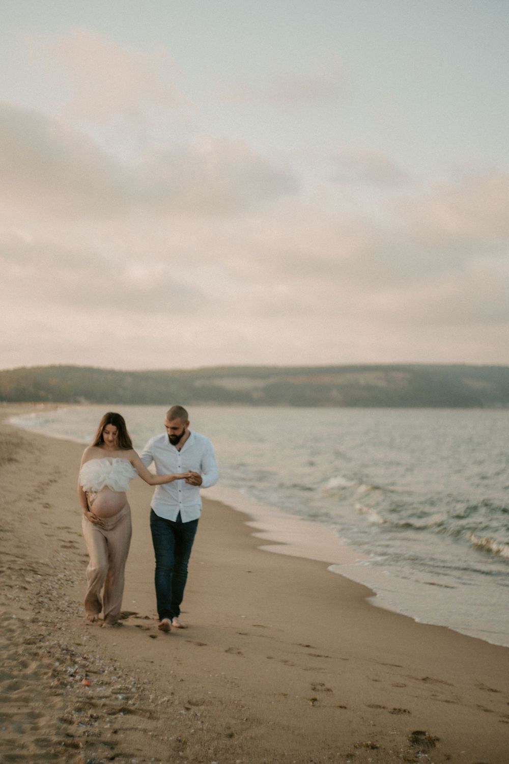 Couple takes a romantic stroll along the shoreline during sunset.