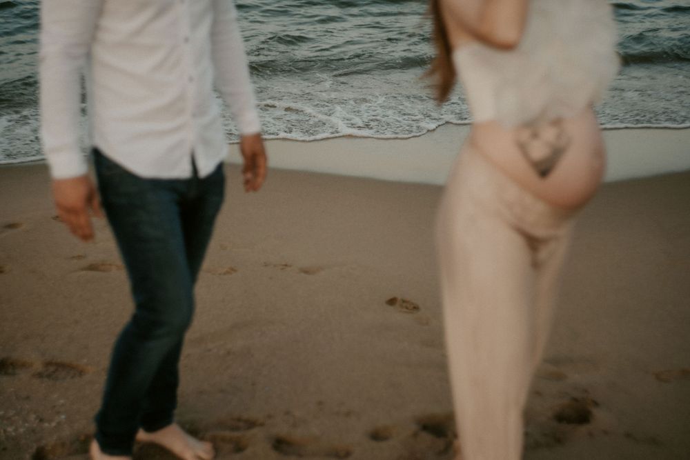 Playful couple dances and spins on the beach during sunset.