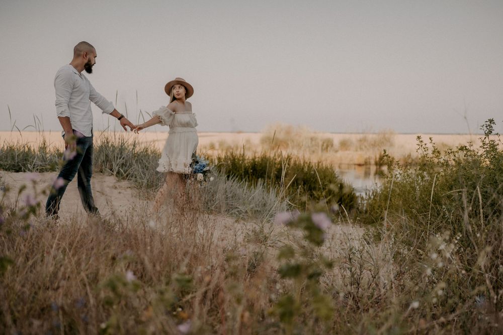 Wide landscape view of couple walking through natural coastal scenery.