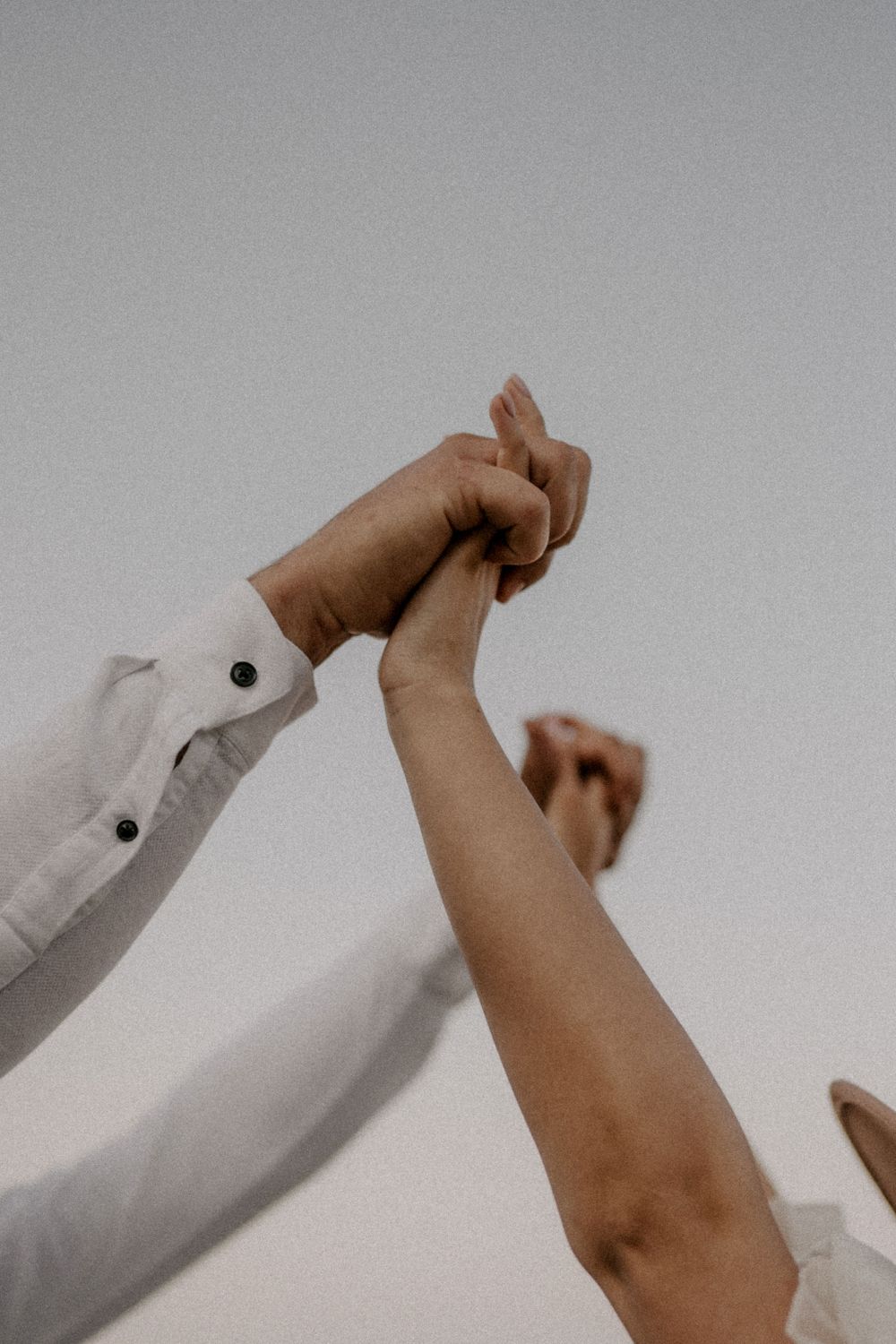 Close-up of two hands clasped together against a light background.