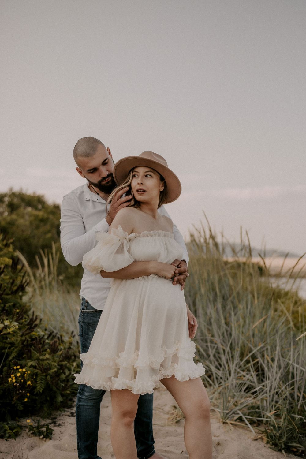 A romantic moment between a couple on a coastal path with beach grass.