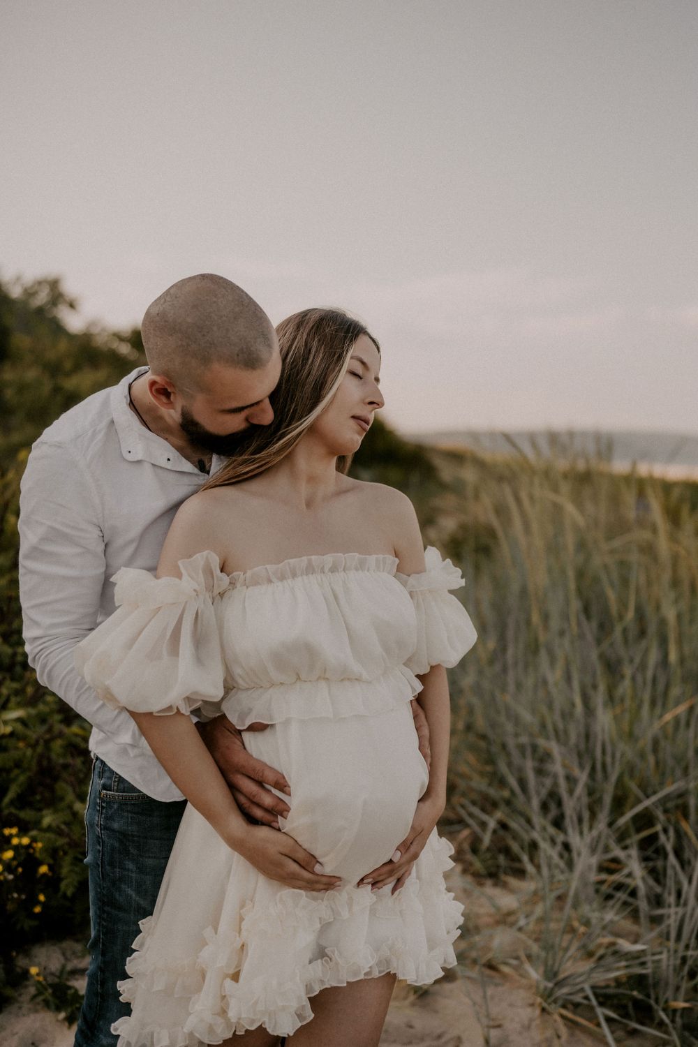 An intimate maternity photo shoot on a beach path at sunset.