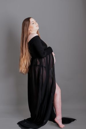 Elegant maternity pose in a flowing black dress showcasing the pregnancy silhouette.