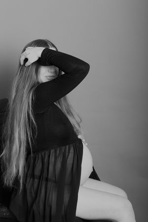 Dramatic black and white maternity photo with artistic pose and flowing fabric.