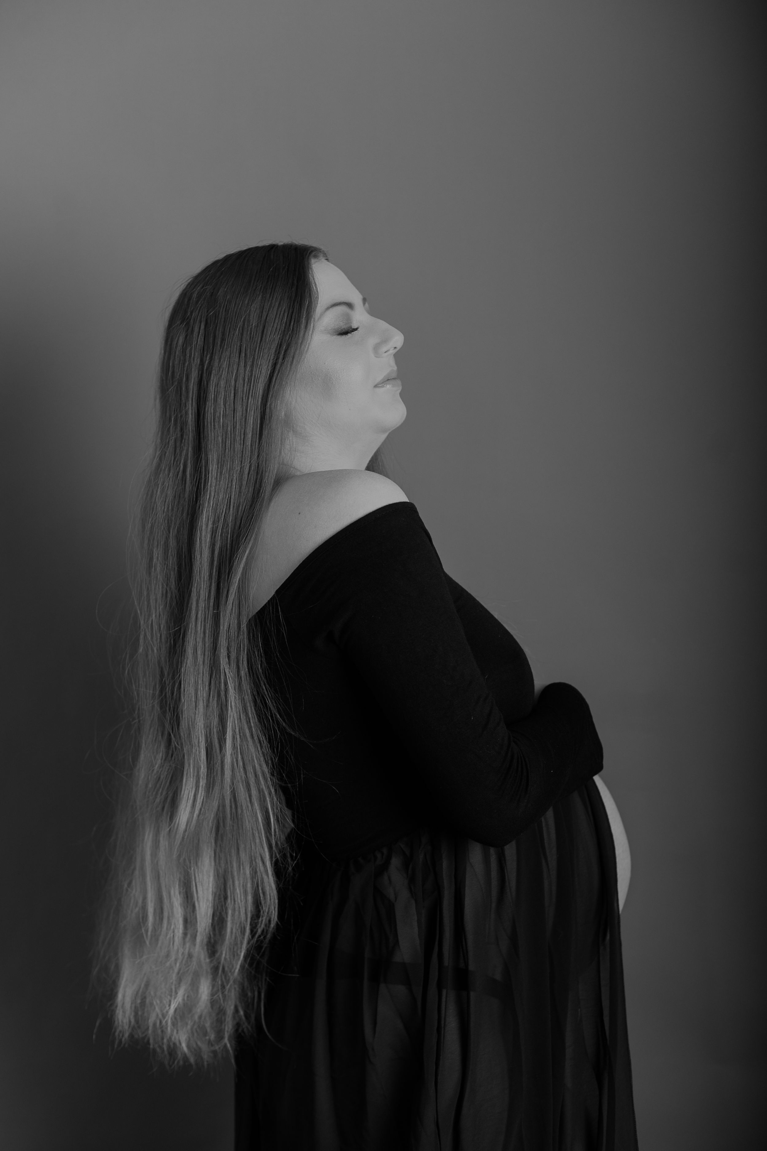 Artistic black and white maternity portrait featuring a flowing black dress.