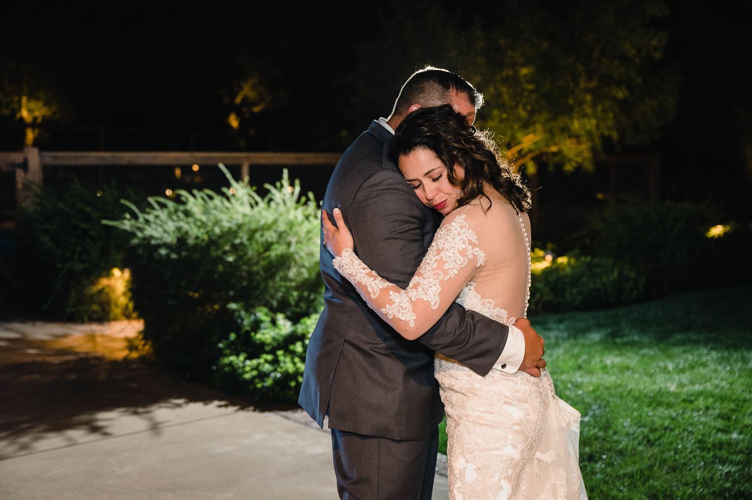 Intimate moment shared during wedding first dance on outdoor patio with garden backdrop.