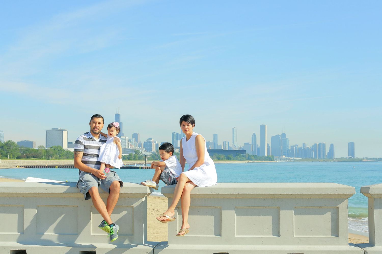 Family members sitting on a concrete wall overlooking the Chicago skyline on a clear day.