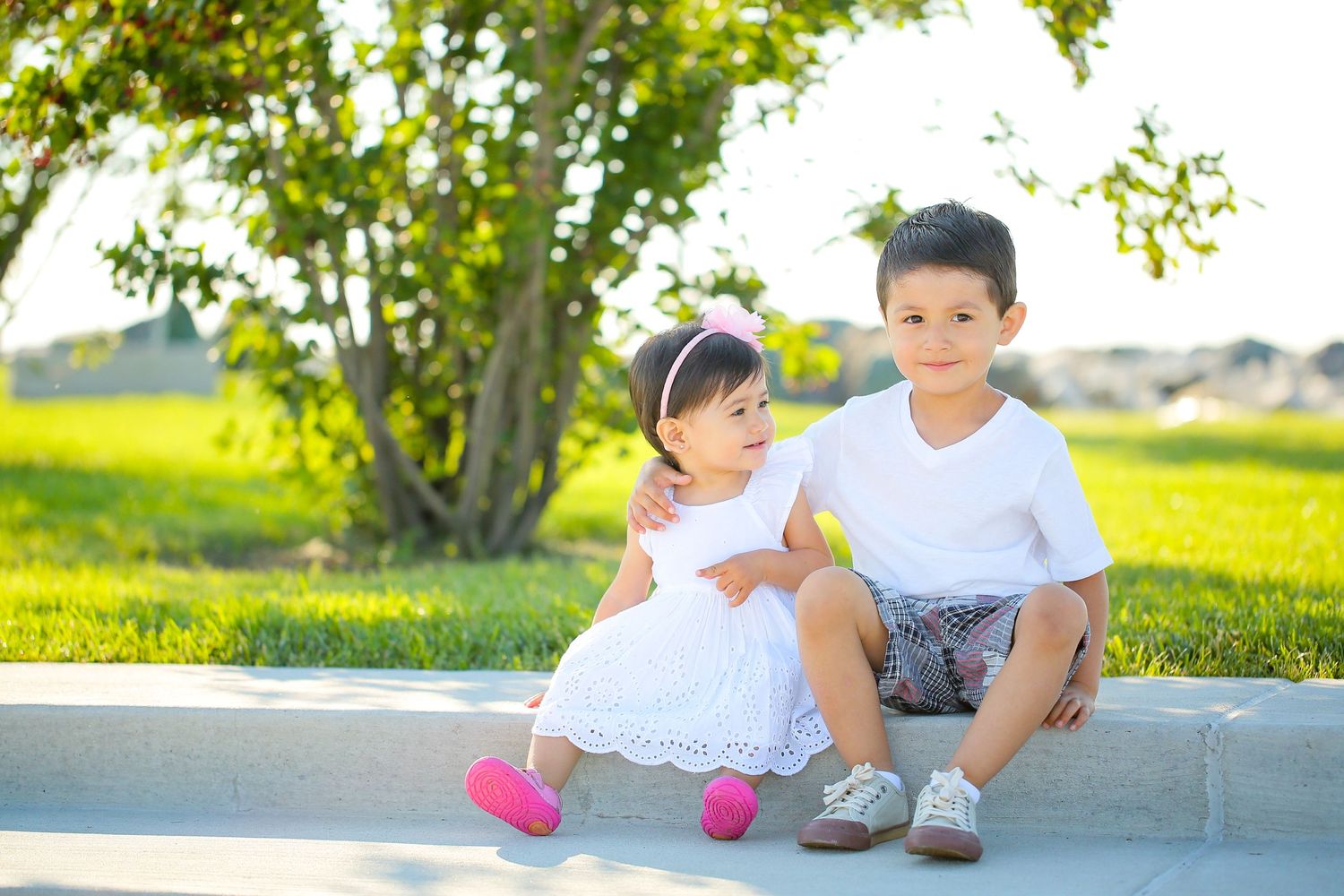 Family members playing together on grass in a sunny park setting.