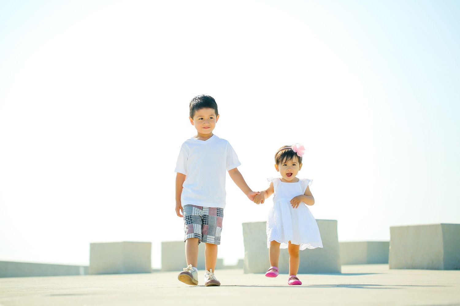 People walking along a bright concrete path with clear sky in the background.