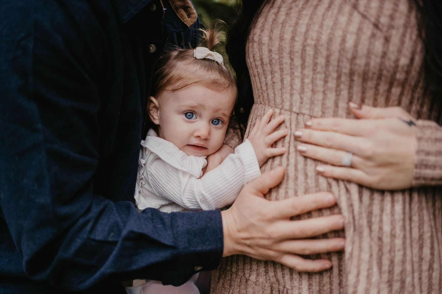 Small child touching pregnant belly in intimate family moment.