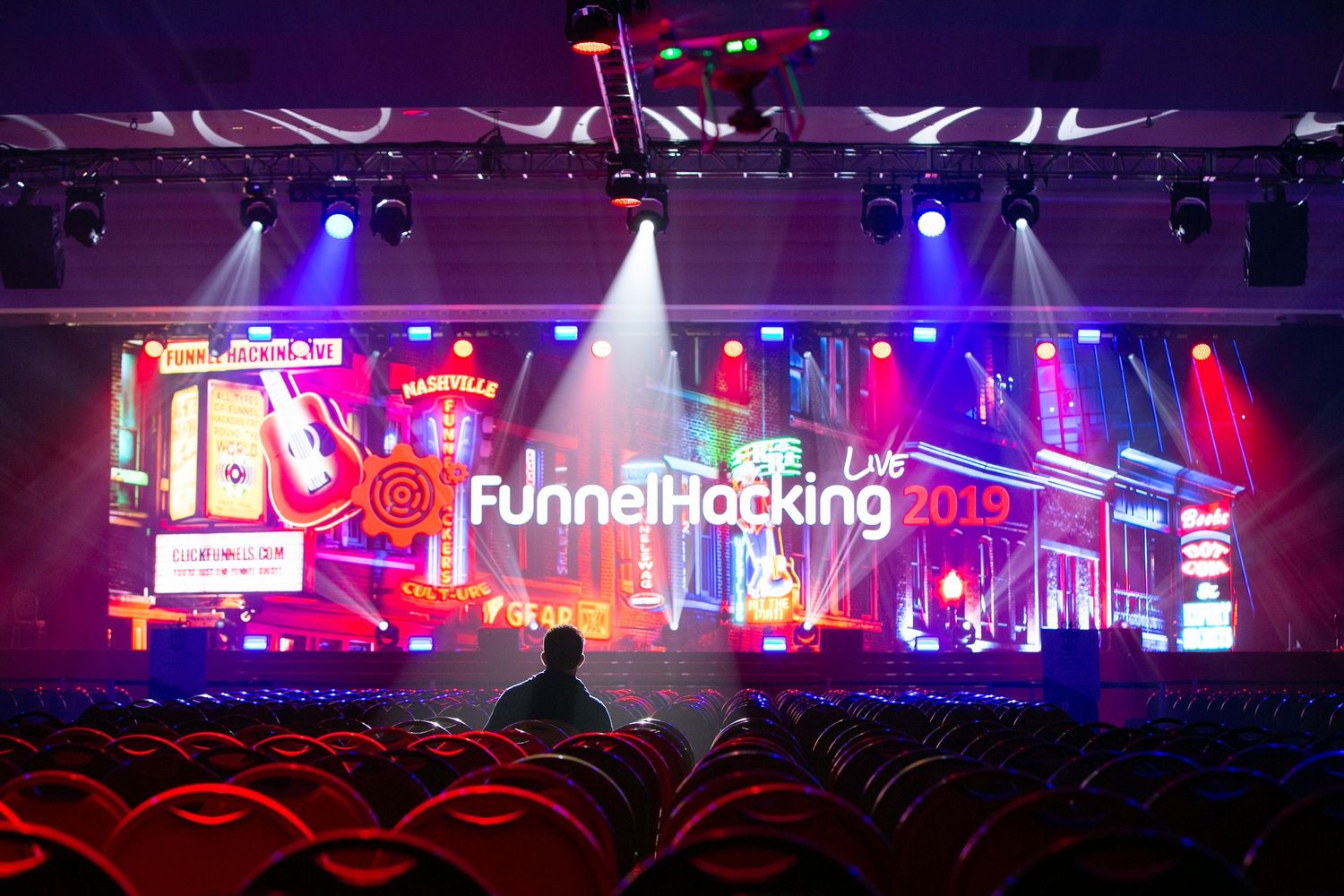Wide concert venue with colorful stage lighting and large LED screens.