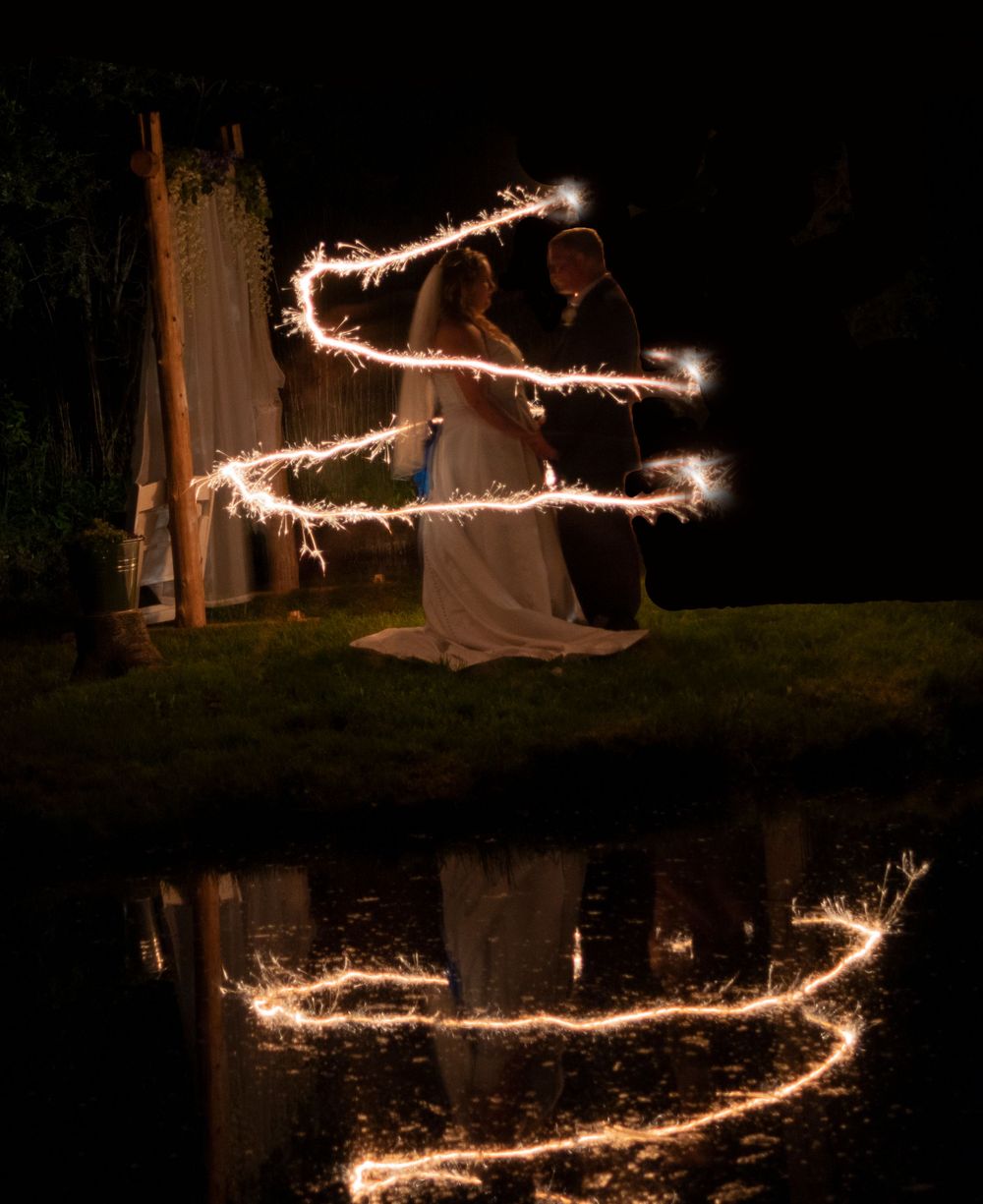 Bride and groom kissing surrounded by a sparkler light