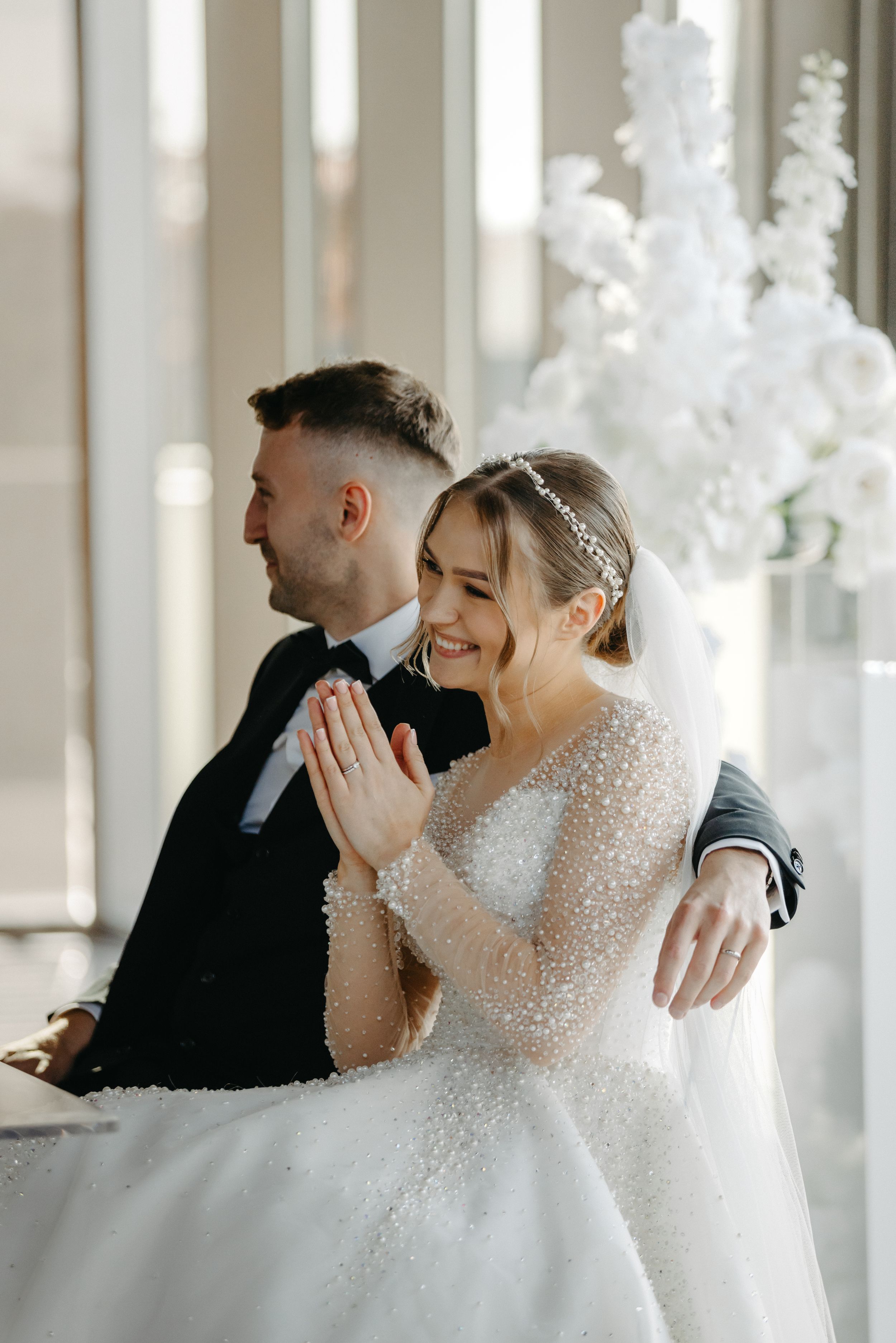 Wedding celebration in a bright sunlit room with white floral decorations.