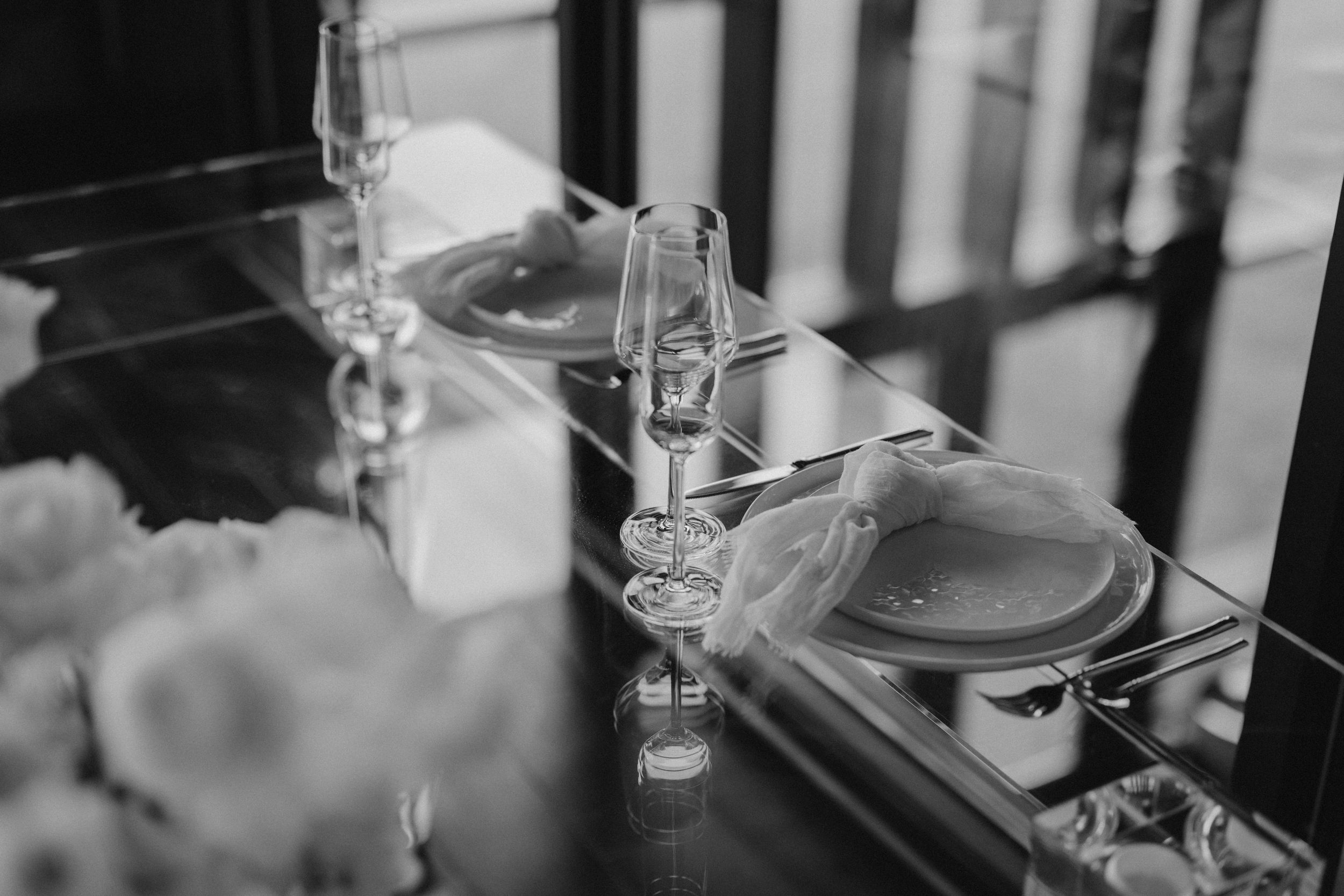 Elegant wedding reception table setting with crystal glasses and place settings captured in black and white.