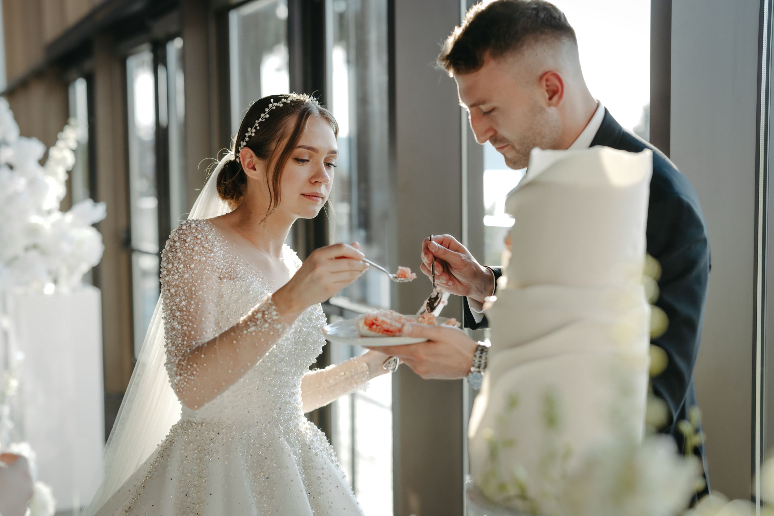 Elegant wedding cake cutting ceremony with white floral decorations.