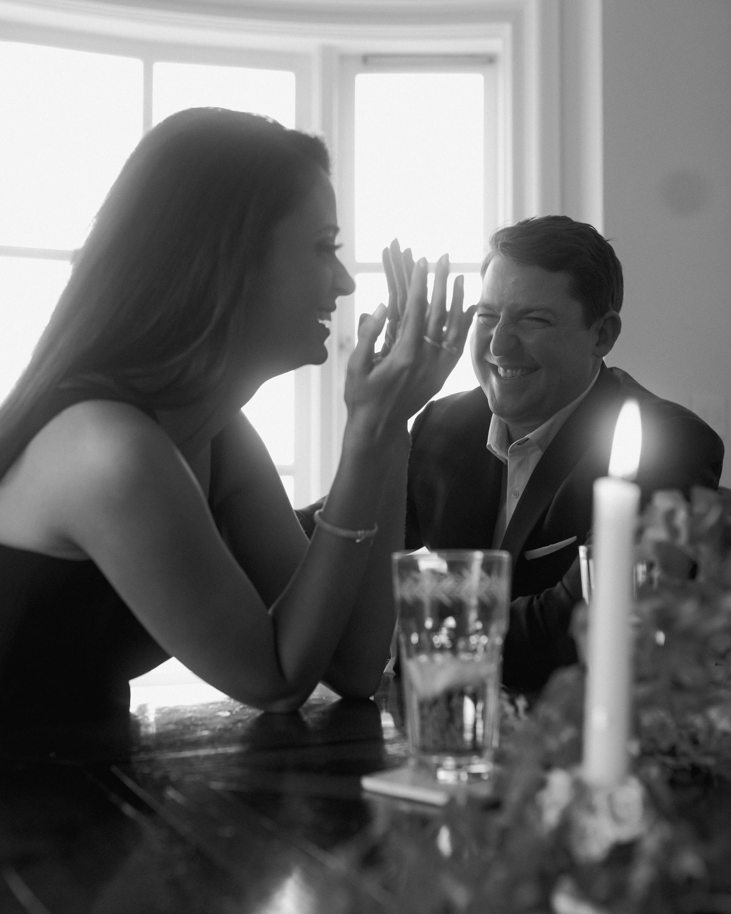 Intimate black and white moment with candlelight and wine glasses.