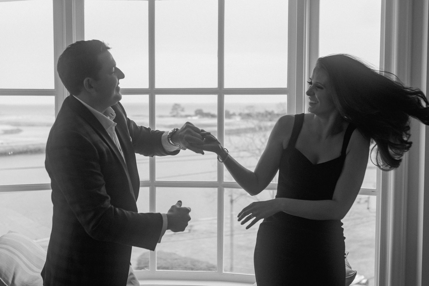 Silhouettes of couple dancing near bright windows in elegant room.