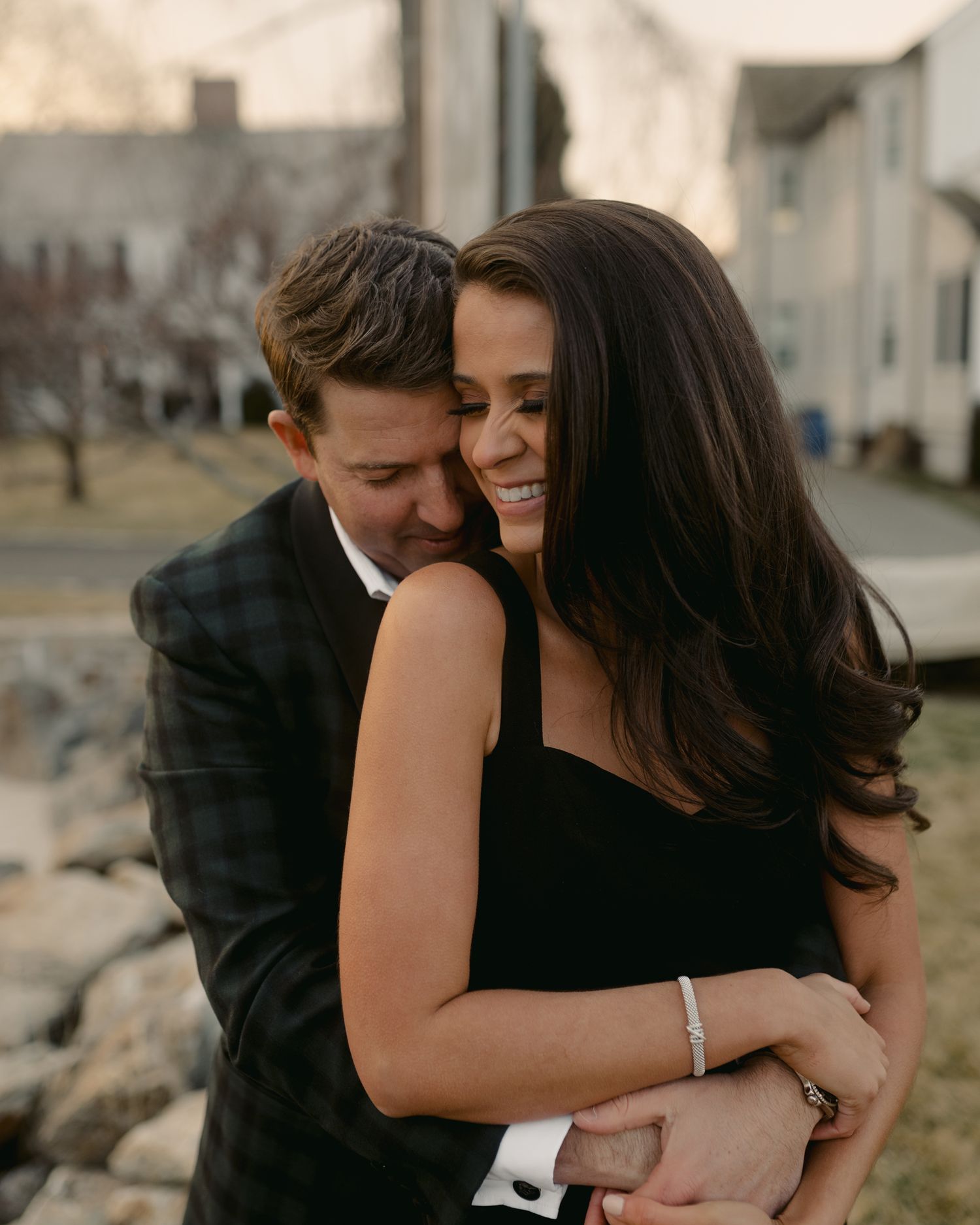 A romantic couple embracing during a sunset photoshoot by the water.