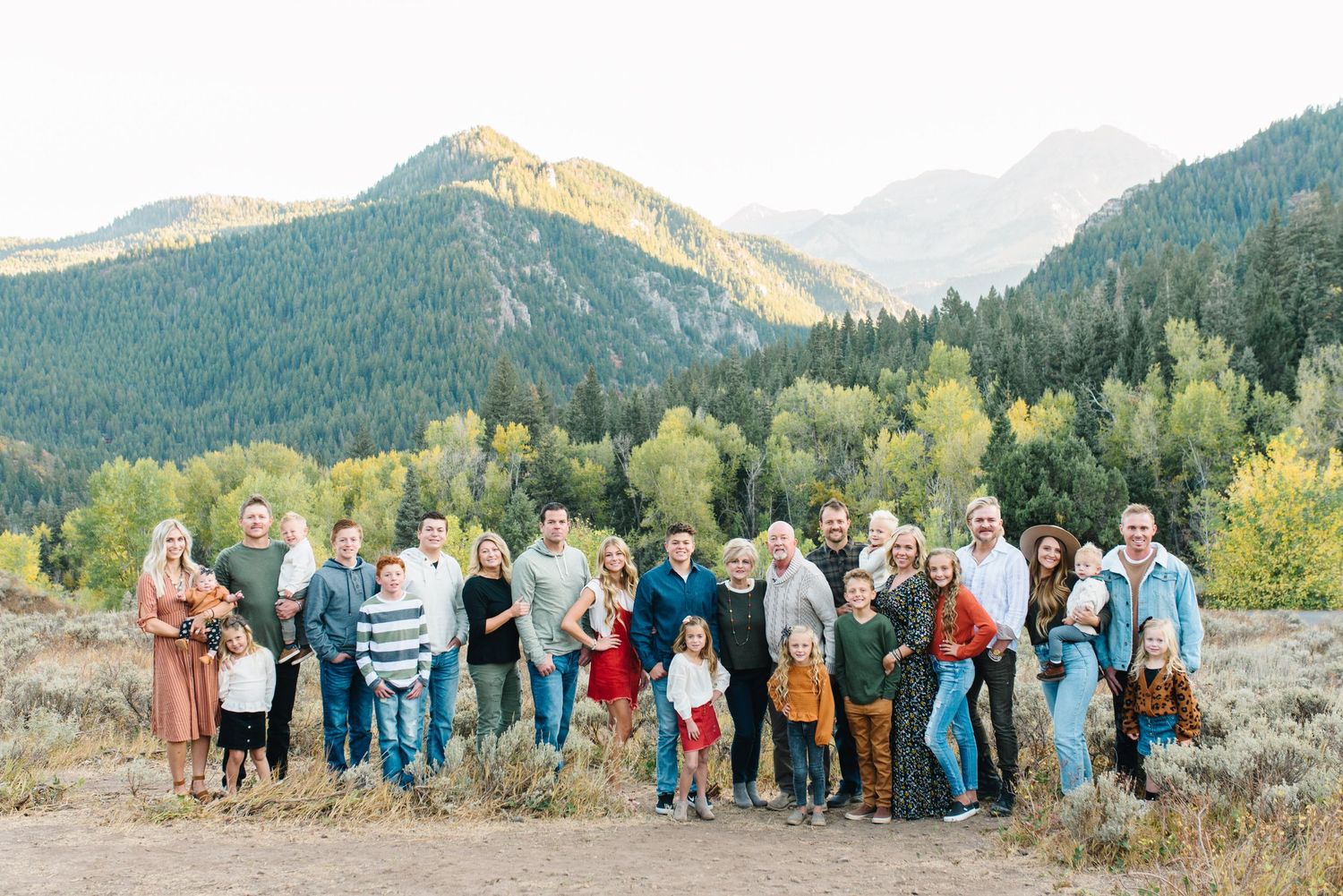 Large family group photo with mountain landscape backdrop during golden hour.
