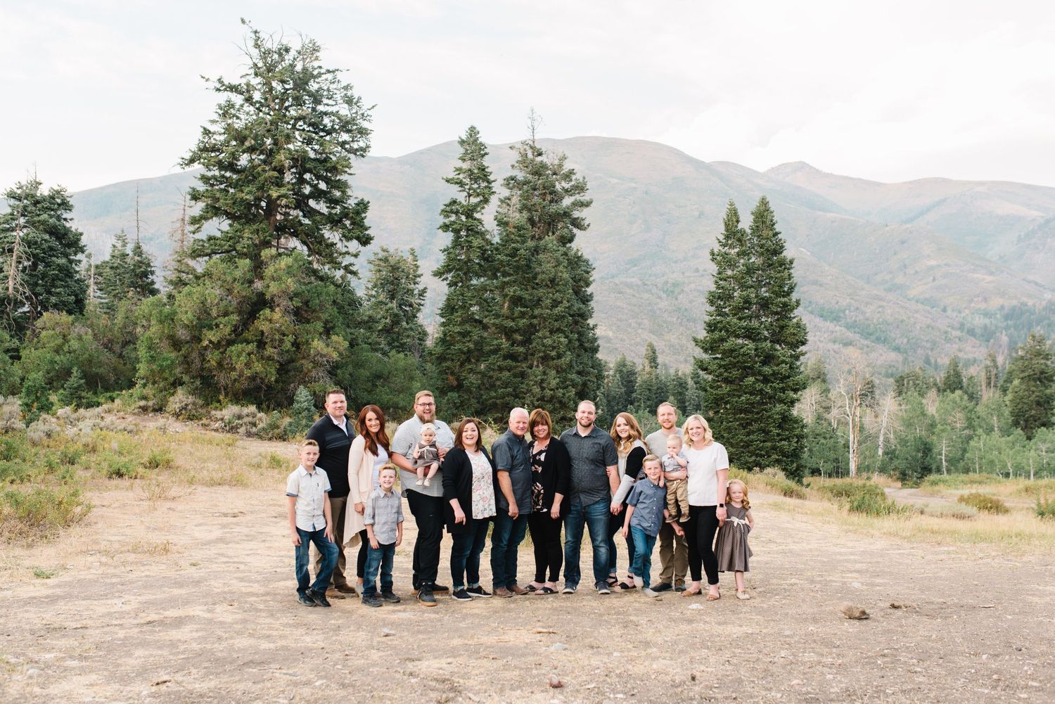 Group portrait of family members against mountain backdrop and evergreen trees.