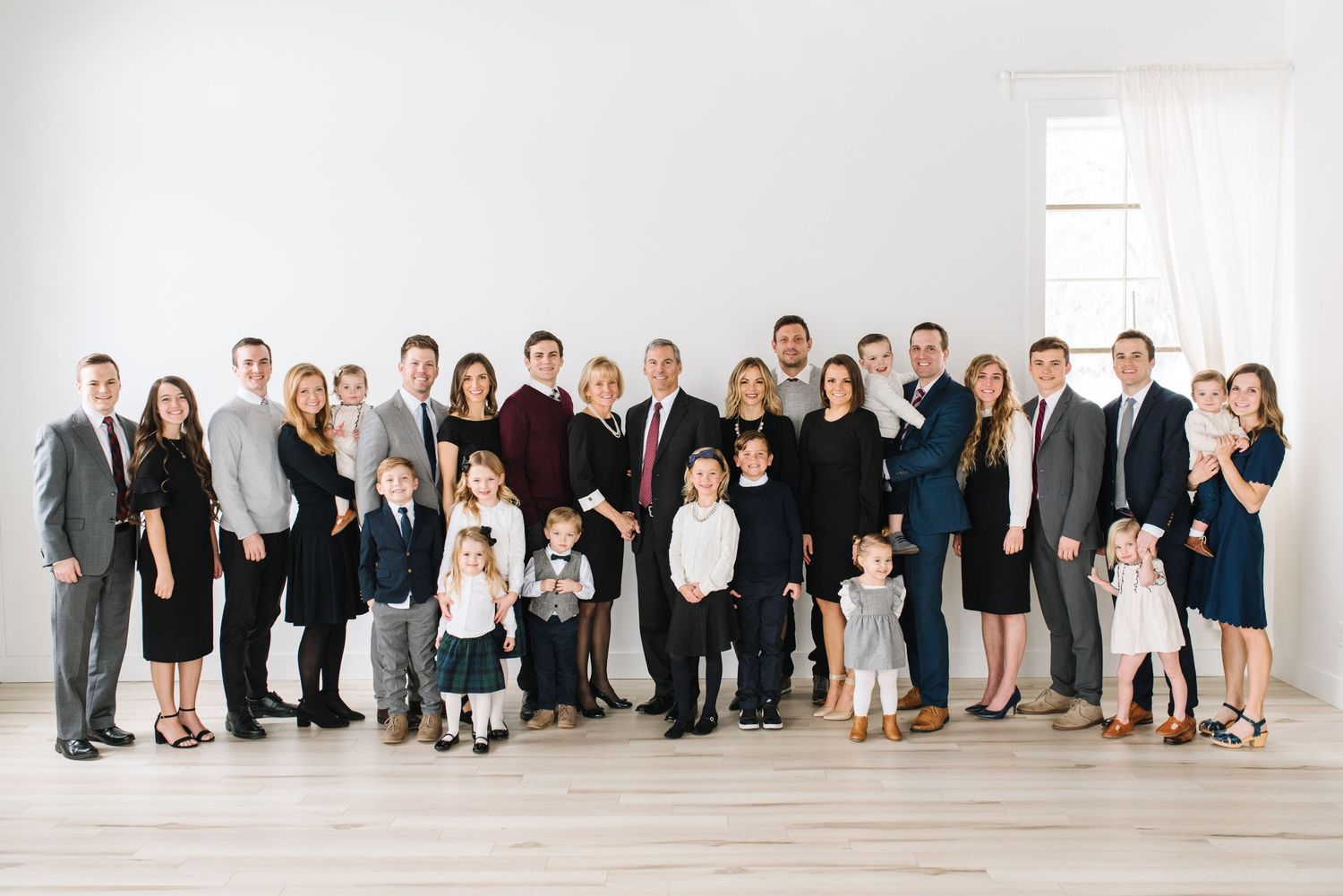 Formal group portrait in black and white attire against a minimalist white studio background.