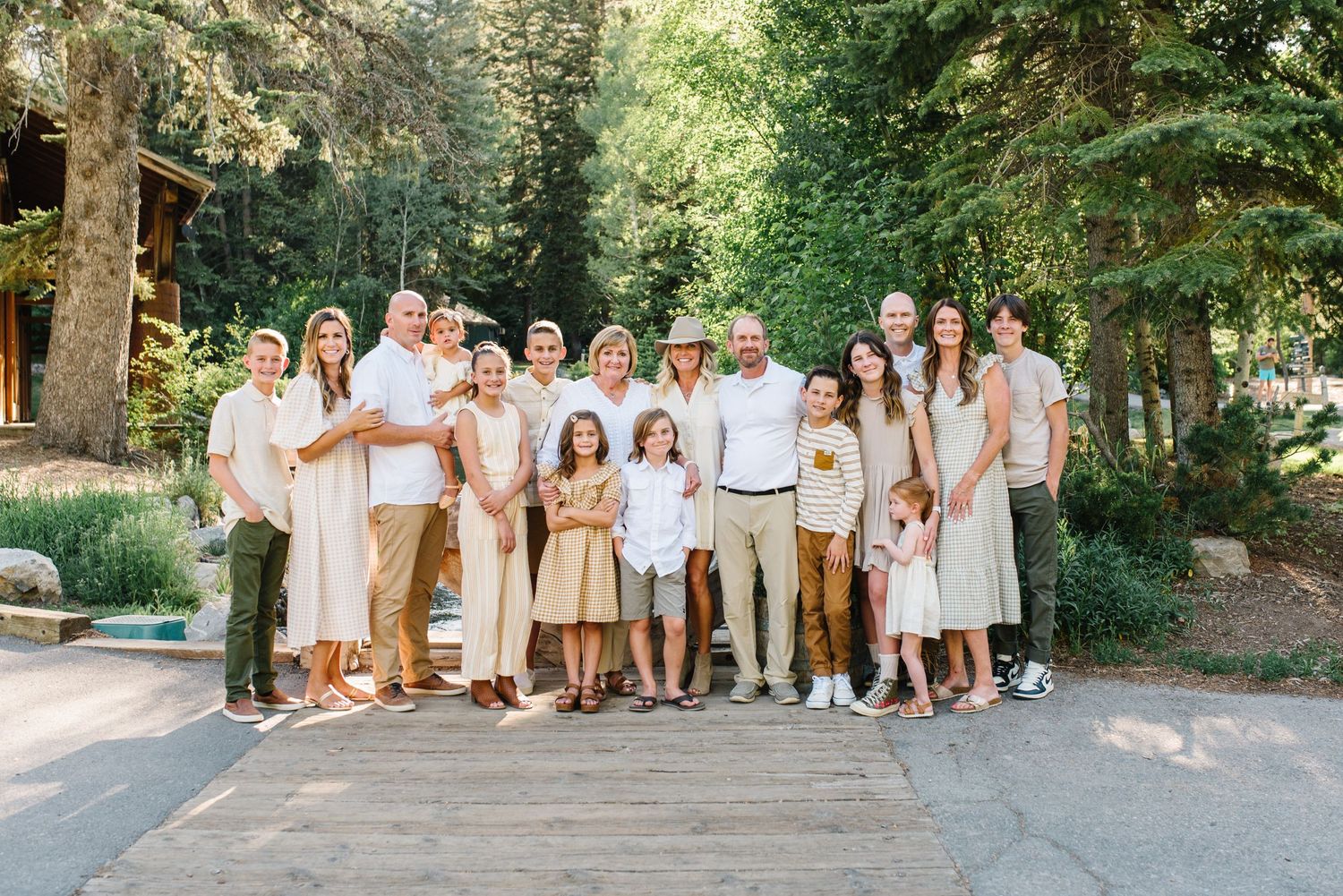 Group photo of people wearing neutral colors standing together on a wooden deck surrounded by trees.