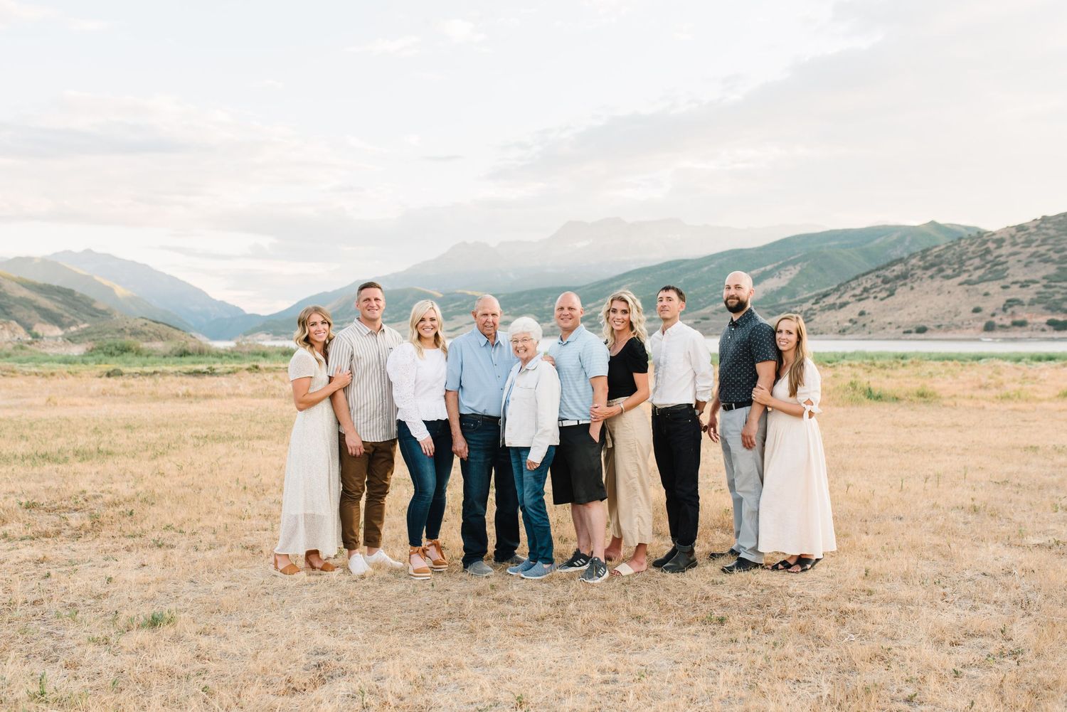 Group portrait of people in coordinated outfits standing in an open field with mountains in the background.