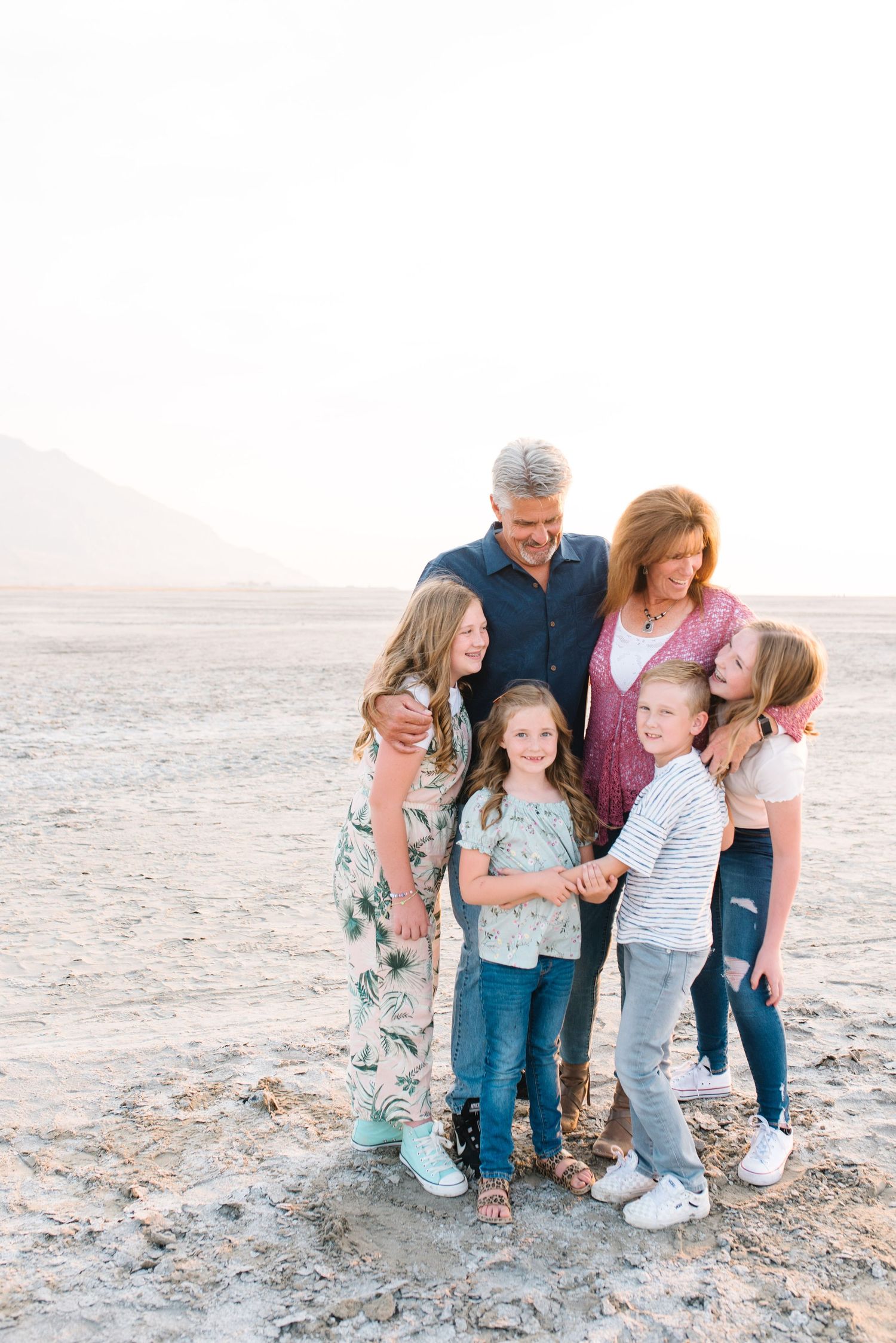 A family group huddles together on a desert landscape at sunset.