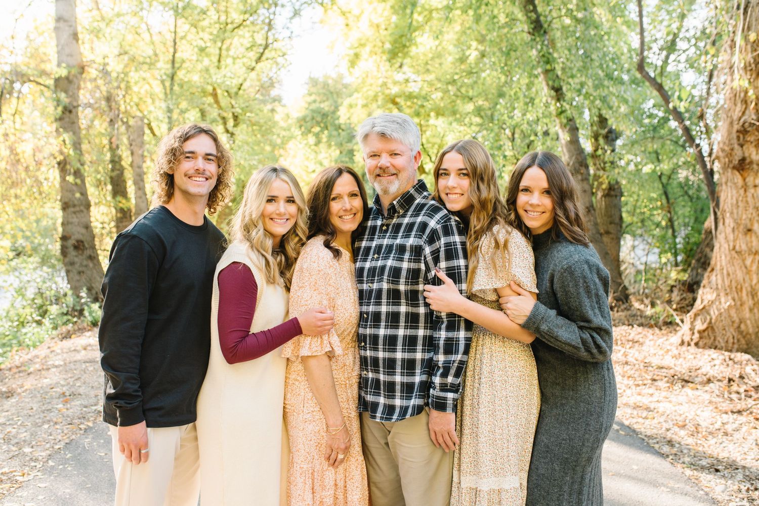 Family members pose together against autumn trees in natural lighting.