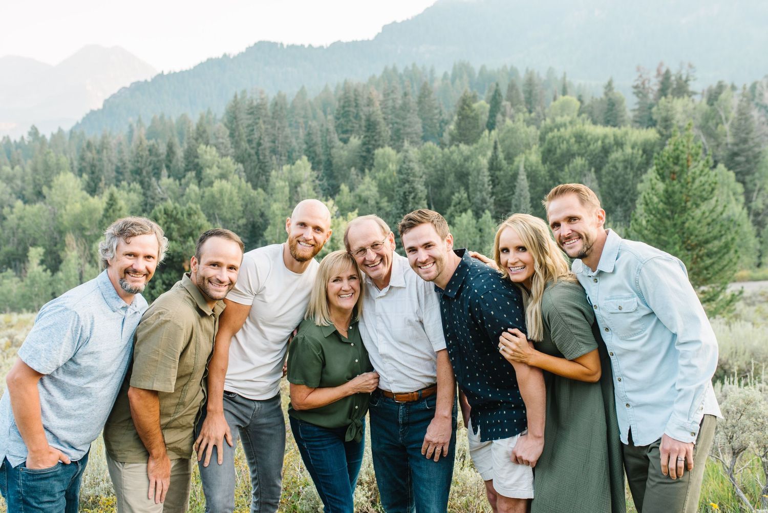 Casual group photo with mountain landscape and pine trees in background.