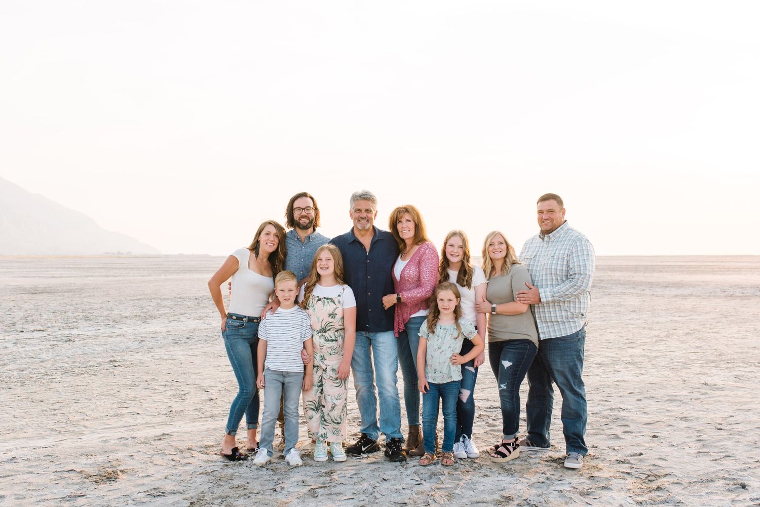 Extended family group photo taken on a salt flat with mountains visible in the distance.