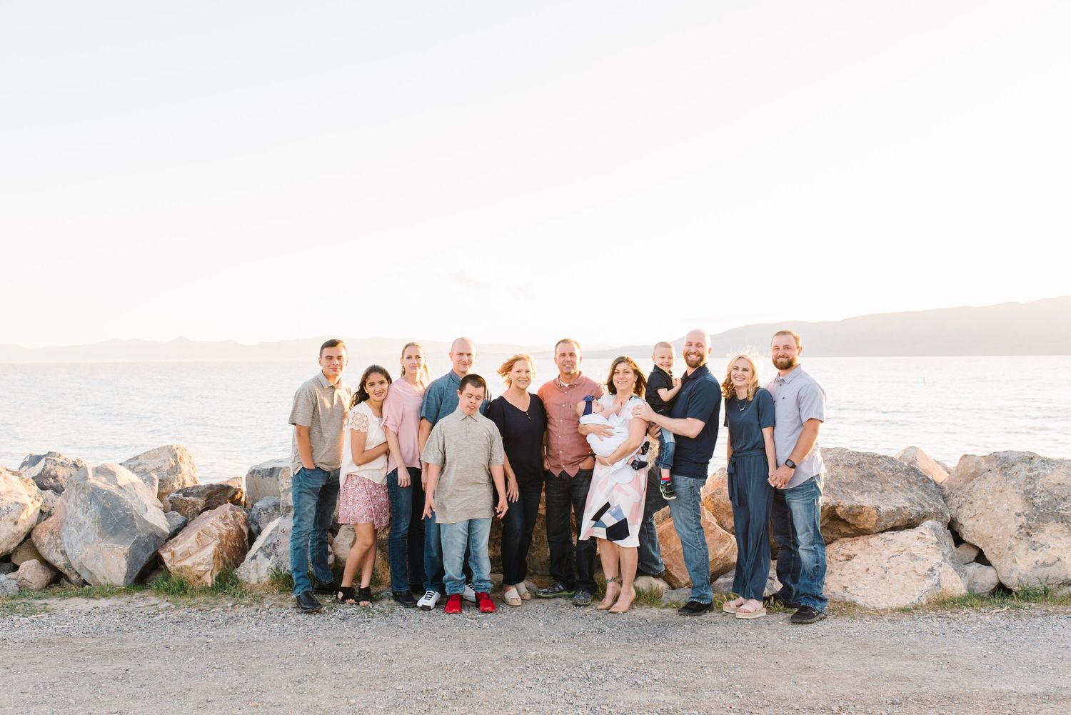 Extended family gathered on rocky shoreline at sunset.
