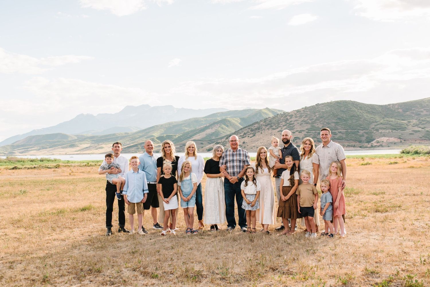 Large group gathered in a field with mountains and clear skies creating a scenic backdrop.