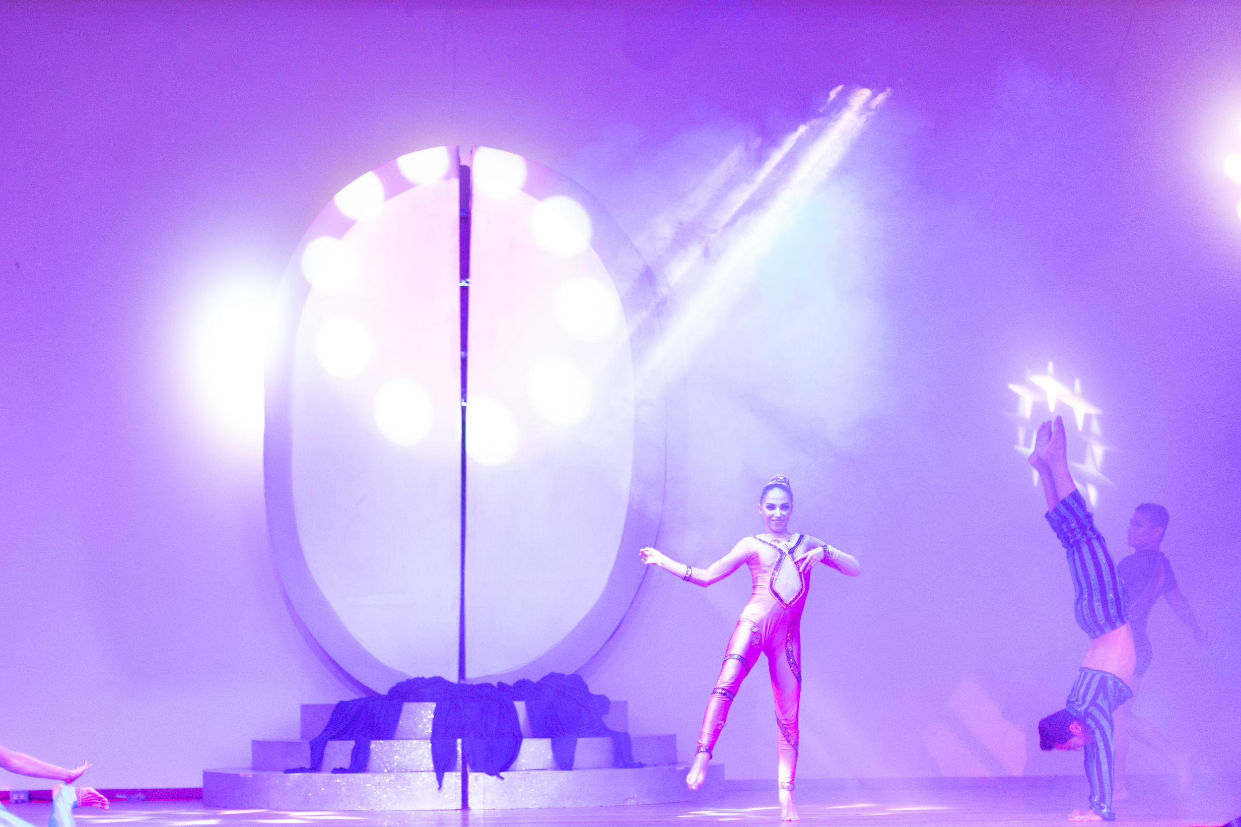 Purple-lit stage performance with dramatic lighting effects and silhouetted figures.