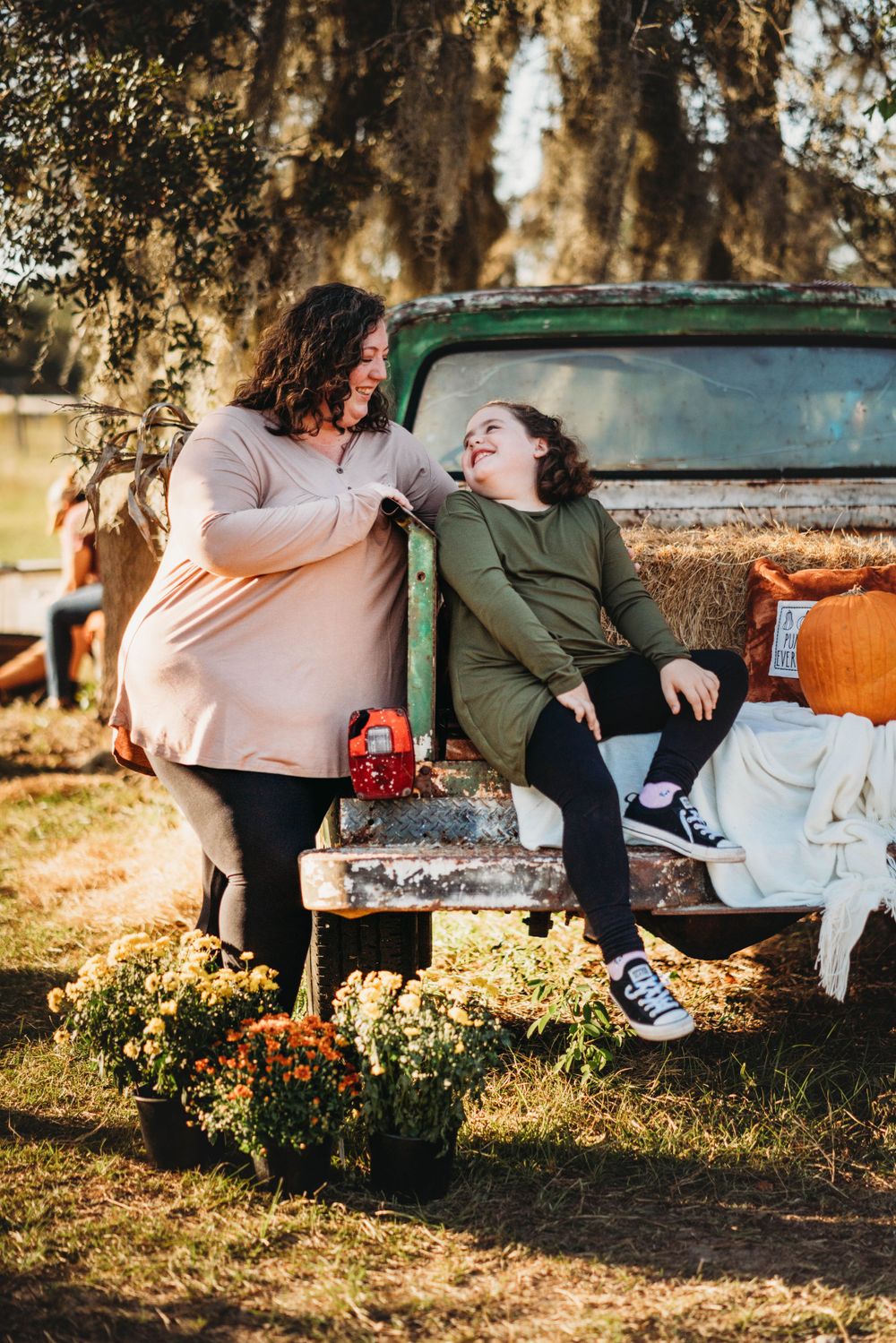 Two people share a lighthearted moment while sitting on vintage truck tailgate with fall decorations.
