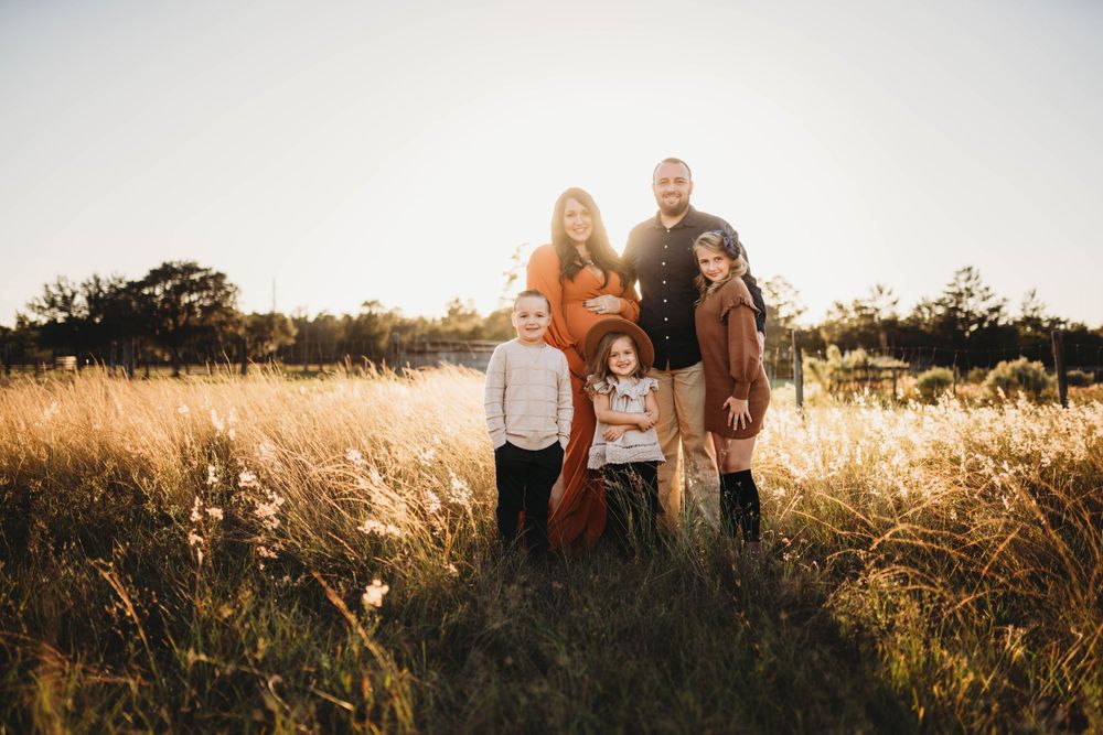 A family portrait at golden hour in tall grass with autumn colors.