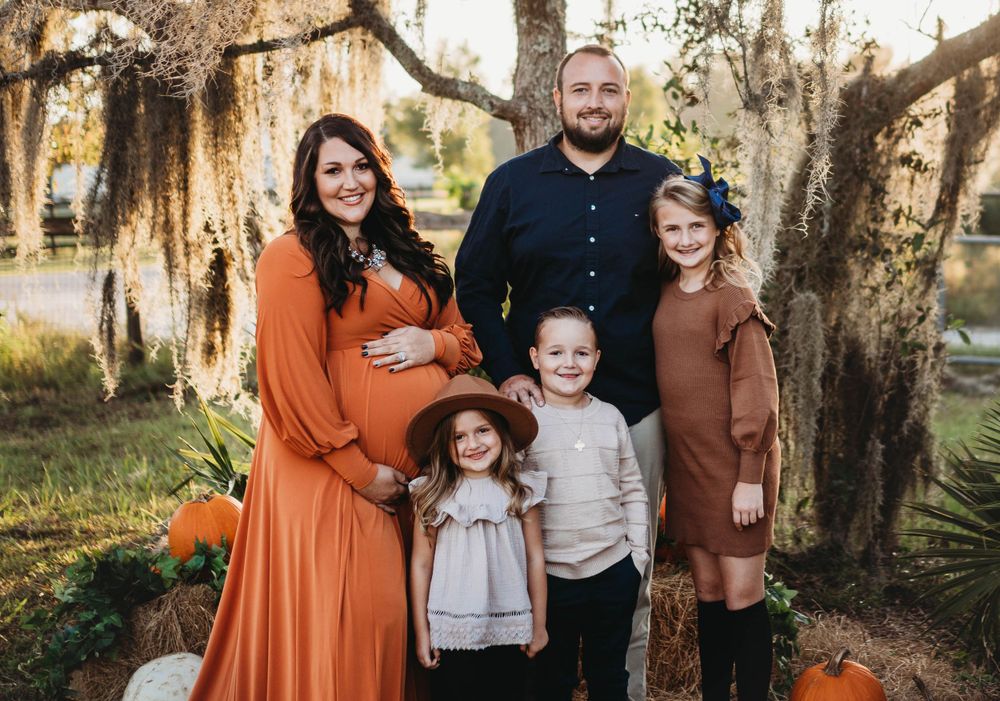 A family autumn portrait with pumpkins and rustic fall decor.