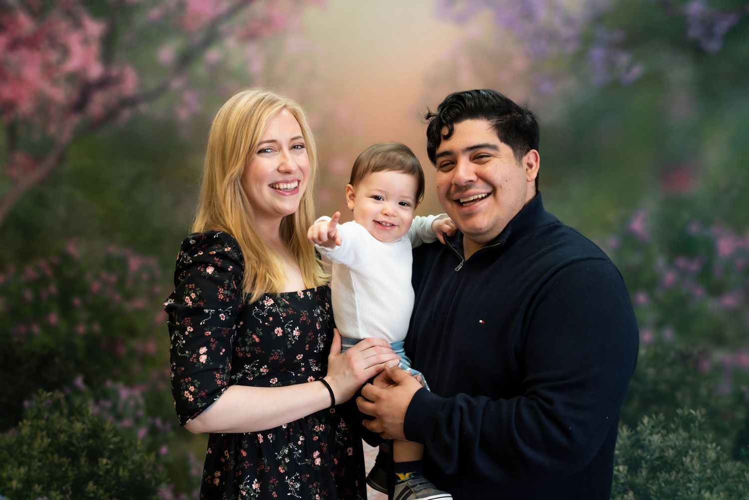 Family enjoying playful moments together among blooming purple and pink flowers.